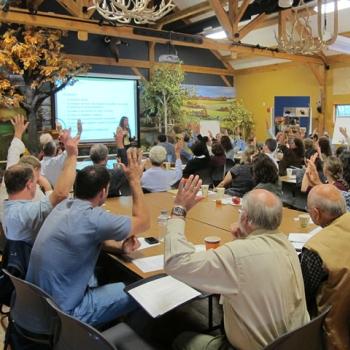 people in a meeting raising hands